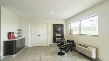 A room with a kitchenette, a dining area, and a large window.