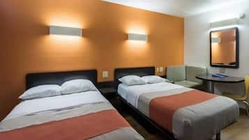 A hotel room with two single beds, a small table, a chair, and a mirror on the wall.
