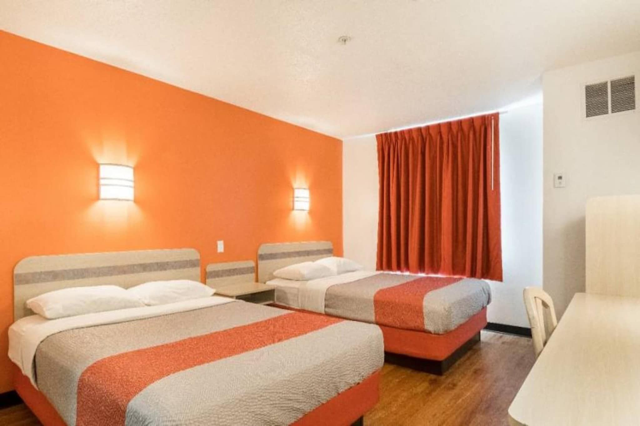 Een hotelkamer met twee bedden, een bureau en een stoel.