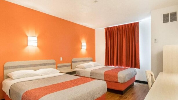Ett hotellrum med två sängar, ett skrivbord och en stol.