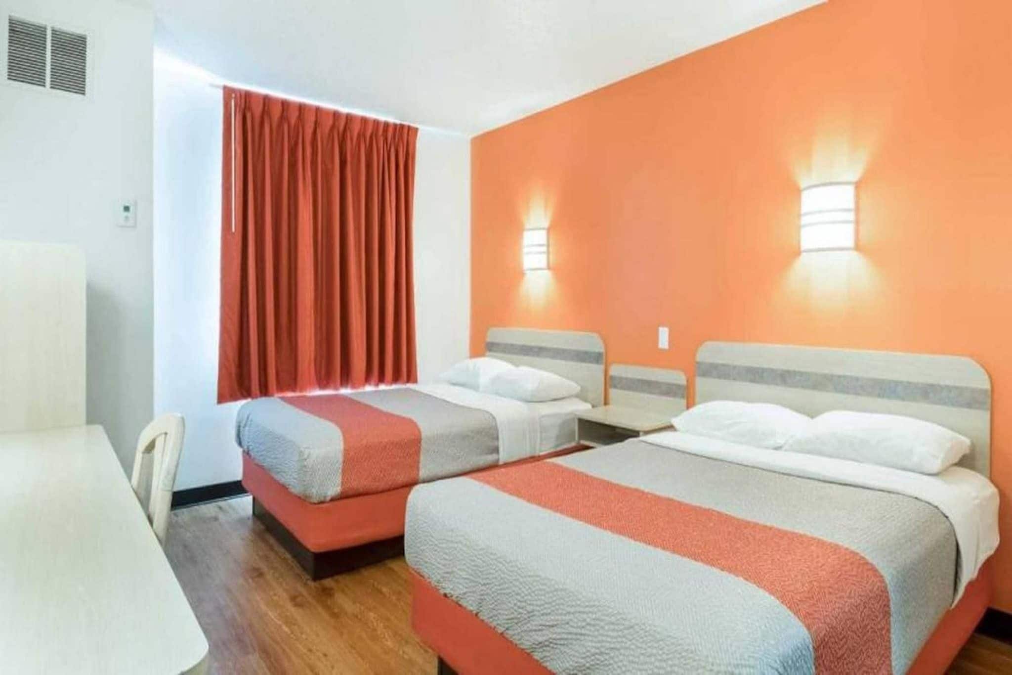 A hotel room with two beds, a desk, and a chair.