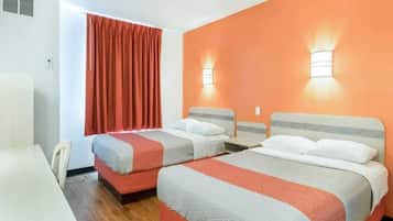 A hotel room with two beds, a desk, and a chair.
