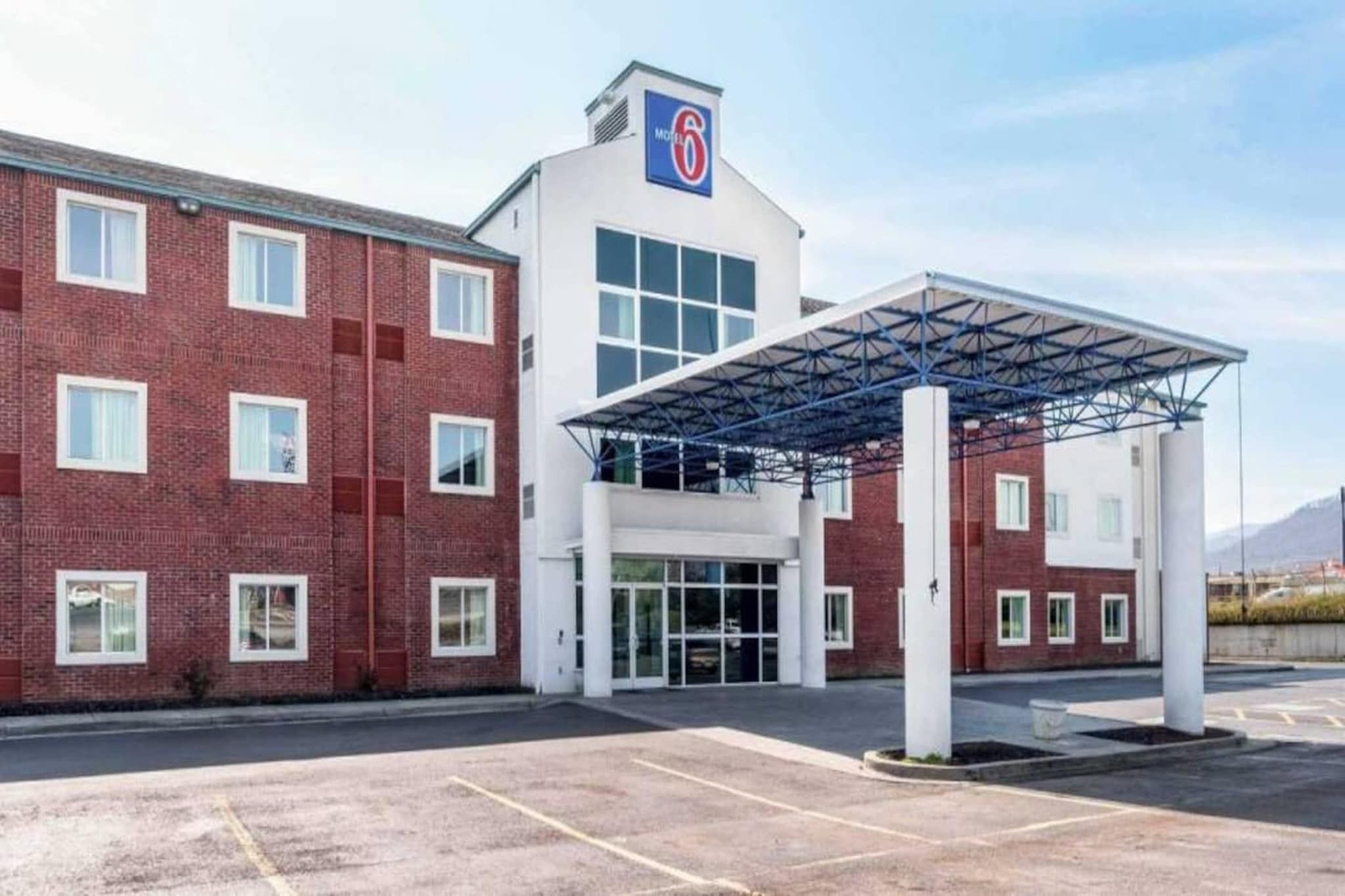 Een hotel met een gevel van rode baksteen, een overdekte ingang en een heldere lucht.