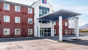 Ett hotell med en fasad av rött tegel, en överbyggd entré och en klar himmel.