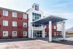 A hotel with a red brick facade, a covered entrance, and a clear sky. - 2 Full Beds | Non-Smoking (Newport)