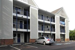 A multi-story hotel with a parking lot and a car parked in front. - Cozy Queen Bed,Free Parking&Wifi,TV (Greensboro)