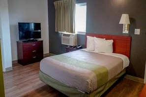 Ein Hotelzimmer mit einem Bett, einem Fernseher, einer Klimaanlage und einer Lampe.