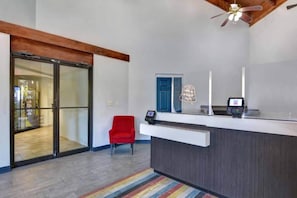 A reception desk with a modern design, a red chair, and a ceiling fan. - 1 Queen Bed | Non-Smoking, Kitchen (Jacksonville)