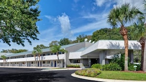 Een hotel met een modern design, met een overdekt buitengebied met palmbomen en een aangelegde tuin.