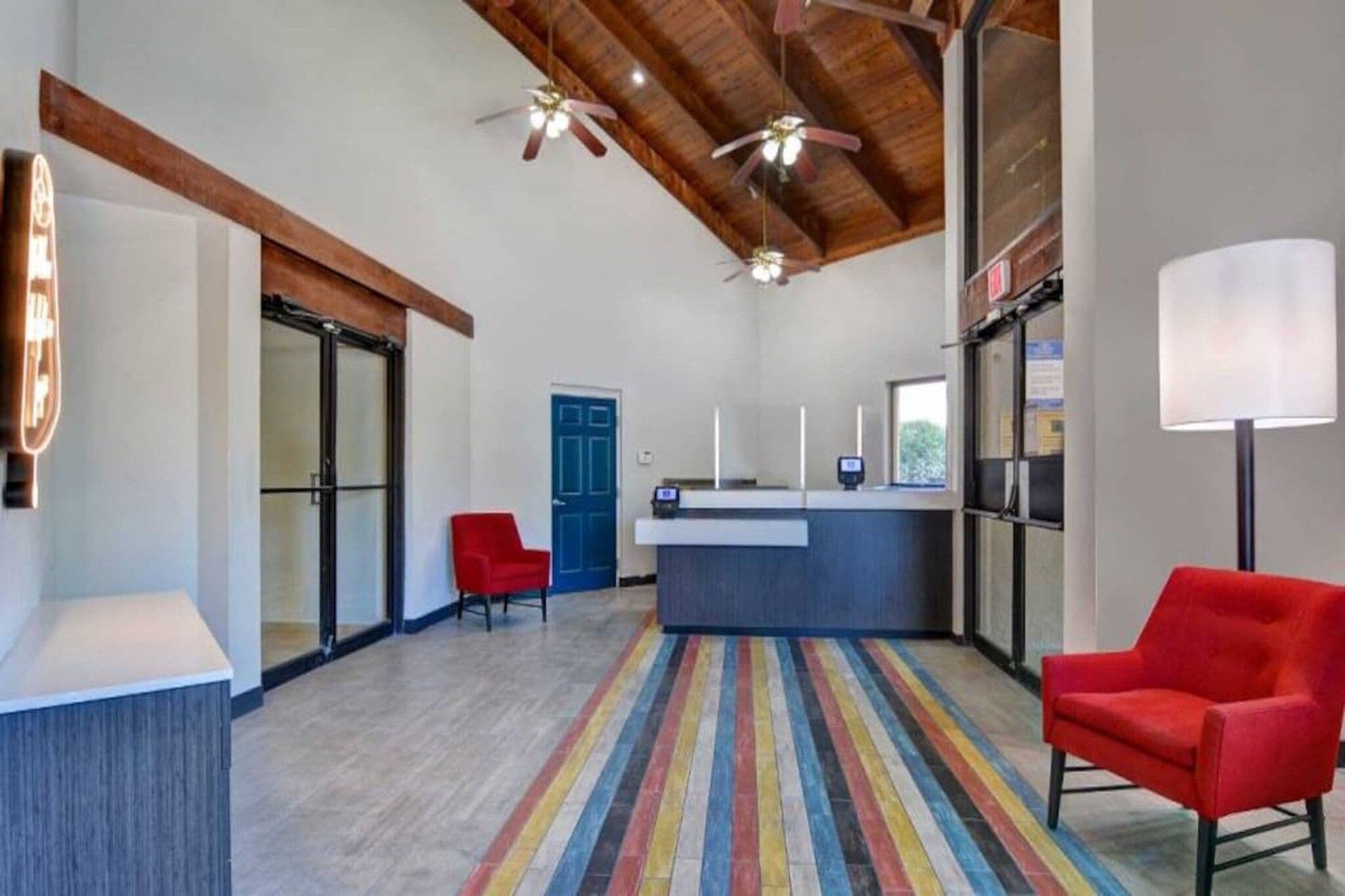 Une cuisine moderne avec un îlot central, une chaise rouge et un tapis coloré à rayures.