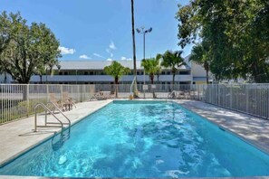 A swimming pool with a metal fence, lounge chairs, and a building in the background. - 1 King Bed|Non-Smoking,Kitchen (Jacksonville)