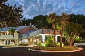 A hotel with a modern design, featuring a covered entrance and a landscaped garden with palm trees. - 1 King Bed|Non-Smoking,Kitchen (Jacksonville)