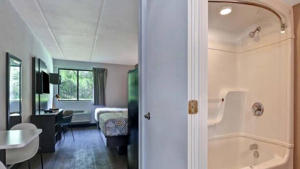 A hotel room with a bed, a desk, a chair, and a large bathtub. - 1 King Bed|Non-Smoking,Kitchen (Jacksonville)