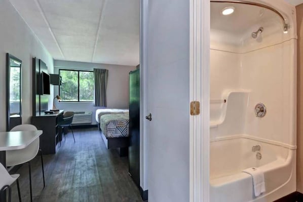 A hotel room with a bed, a desk, a chair, and a large bathtub. - 1 King Bed|Non-Smoking,Kitchen (Jacksonville)