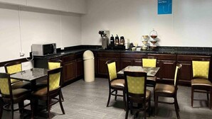 Un comedor de hotel con una barra larga, varias sillas y una estación de café.