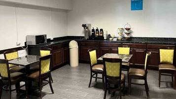 Un comedor de hotel con una barra larga, varias sillas y una estación de café.