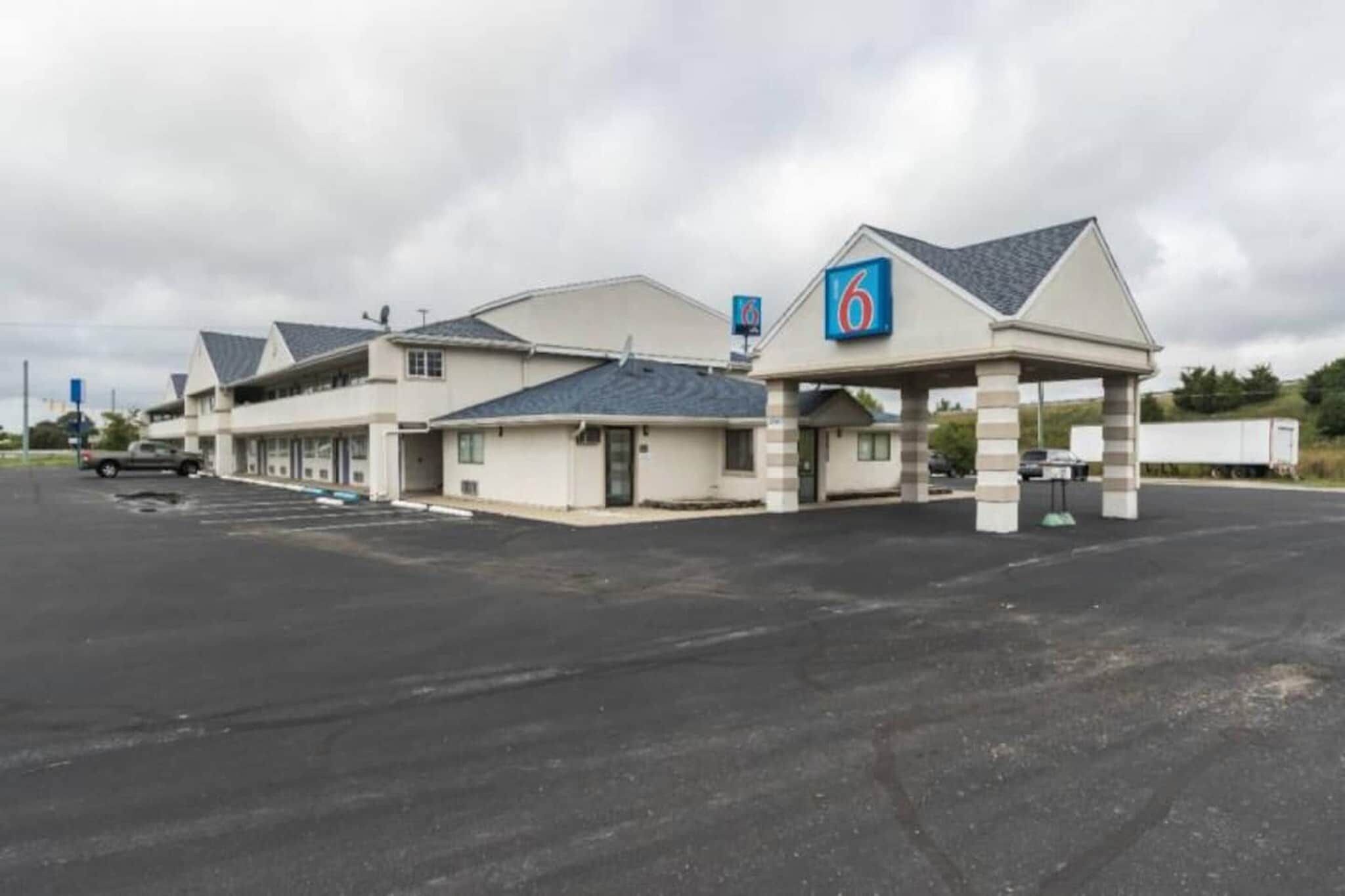 Un motel con un amplio estacionamiento y un edificio de seis unidades.