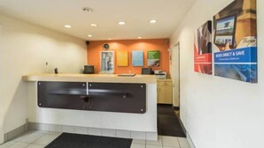 A reception area with a counter, a computer, and a wall with informational posters. - 1 King Bed | Non-Smoking (CRAWFORDSVILLE)