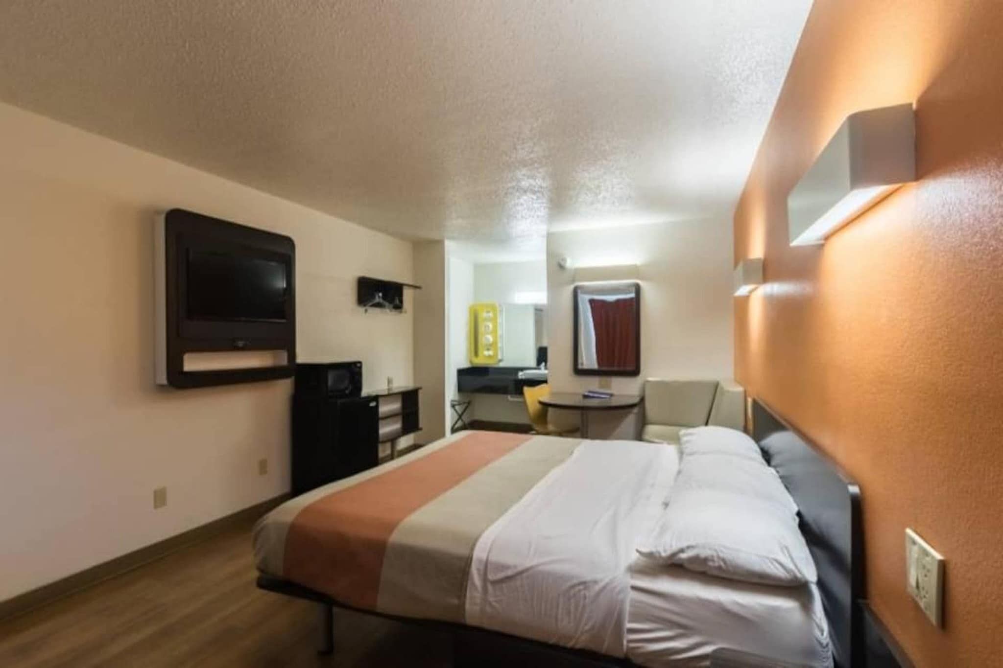 Une chambre d’hôtel équipée d’un lit, d’un bureau, d’une chaise, d’une télévision et d’un miroir.