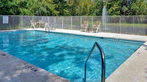 A swimming pool with a metal ladder, surrounded by a fence and chairs. - 1 King Bed|Mobil Access Tub|Nsmk|Kitchen (Jacksonville)