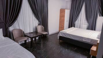 A hotel room with a bed, a desk, two chairs, and a wardrobe.