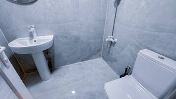 A bathroom with a white sink, toilet, and shower.