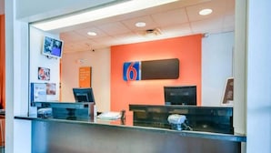 Una recepción con un cartel grande con el número 6, un televisor montado en la pared y algunas fotografías enmarcadas.