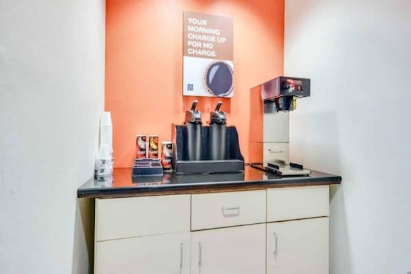 A coffee station with a coffee machine, cups, and a sign offering a morning charge for no charge. - 1 Queen Bed | Micfridge (Biloxi)