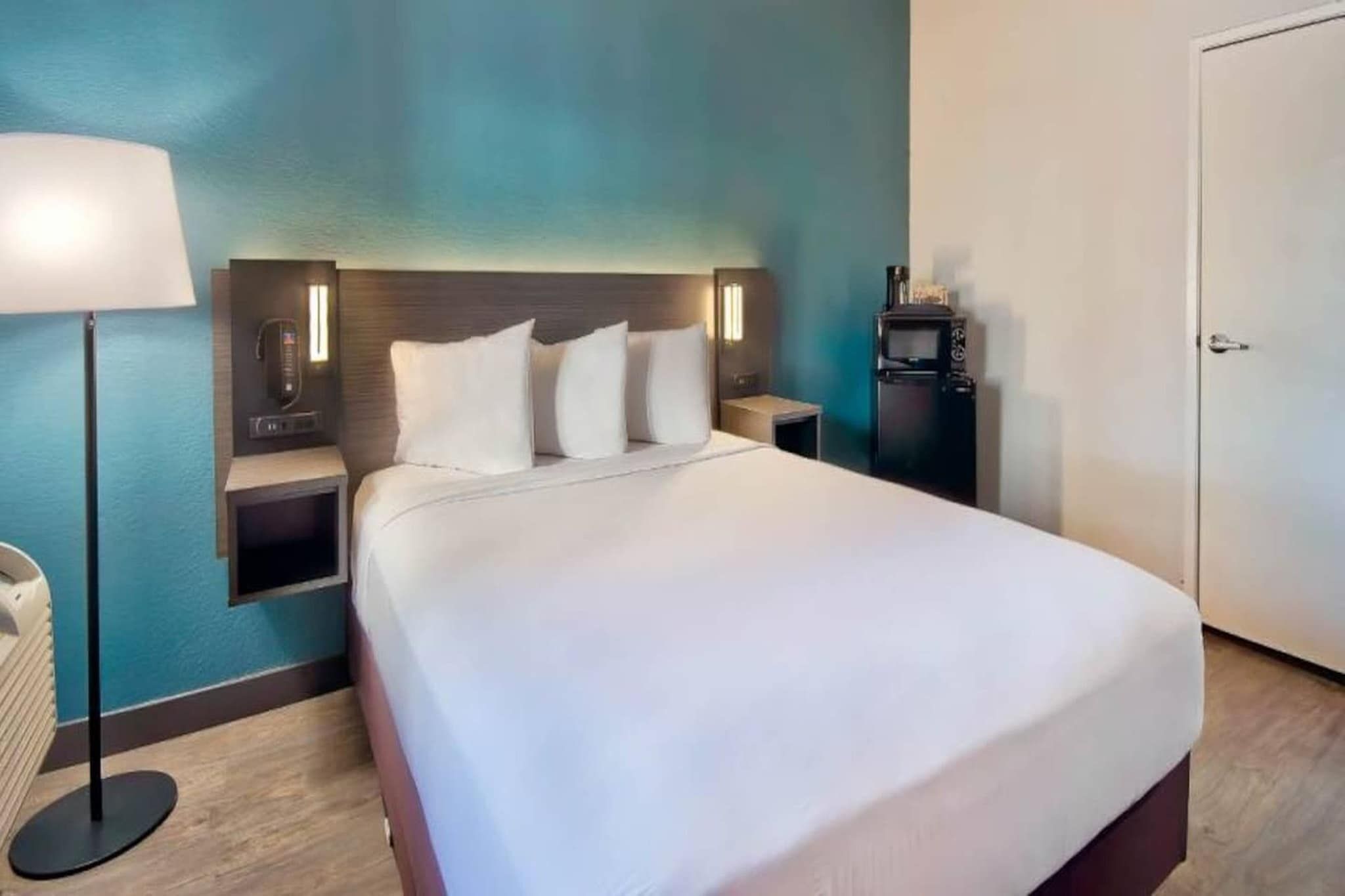Ein Hotelzimmer mit einem Bett, Nachttischen, einer Lampe, einem Heizkörper und einem Kleiderschrank.