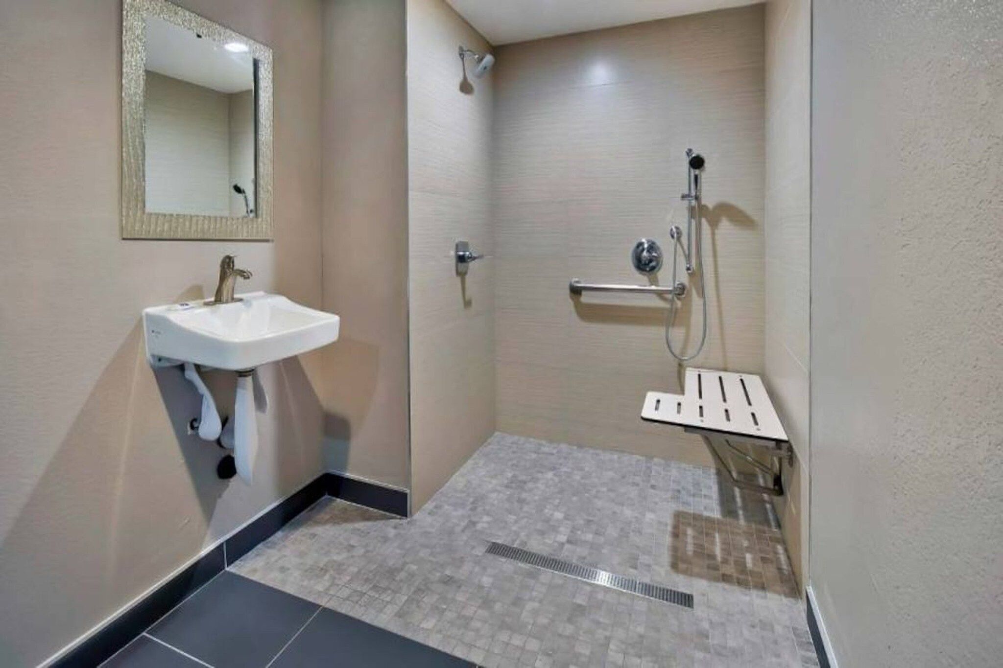 Ein Badezimmer mit Waschbecken, Spiegel, Dusche und Fliesenboden.