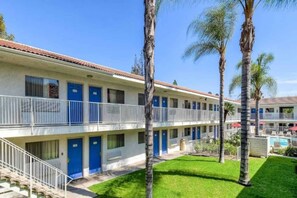 Ein Motel mit mehreren Stockwerken, blauen Türen und einem Poolbereich.