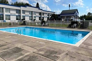 A swimming pool with a 'NO DIVING' sign, surrounded by a fenced area with chairs and a building in the background. - 1 Queen Bed | Smoking, Kitchen (Clarion)