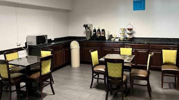 A hotel dining area with a long counter, multiple chairs, and a coffee station.