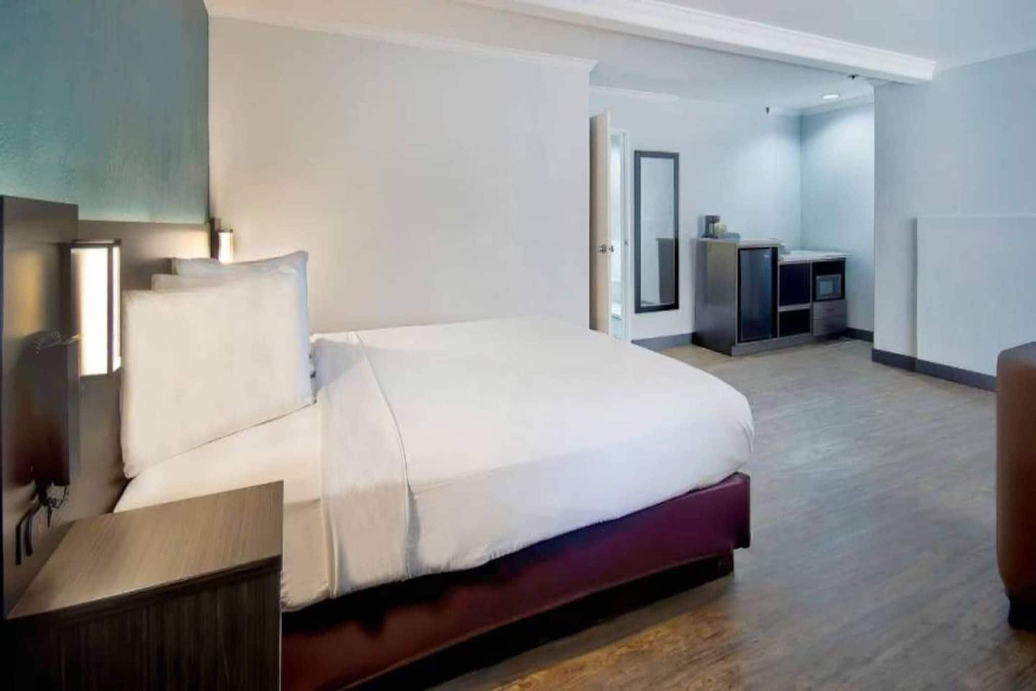 A modern hotel room with a large bed, bedside tables, a desk, and a wardrobe.