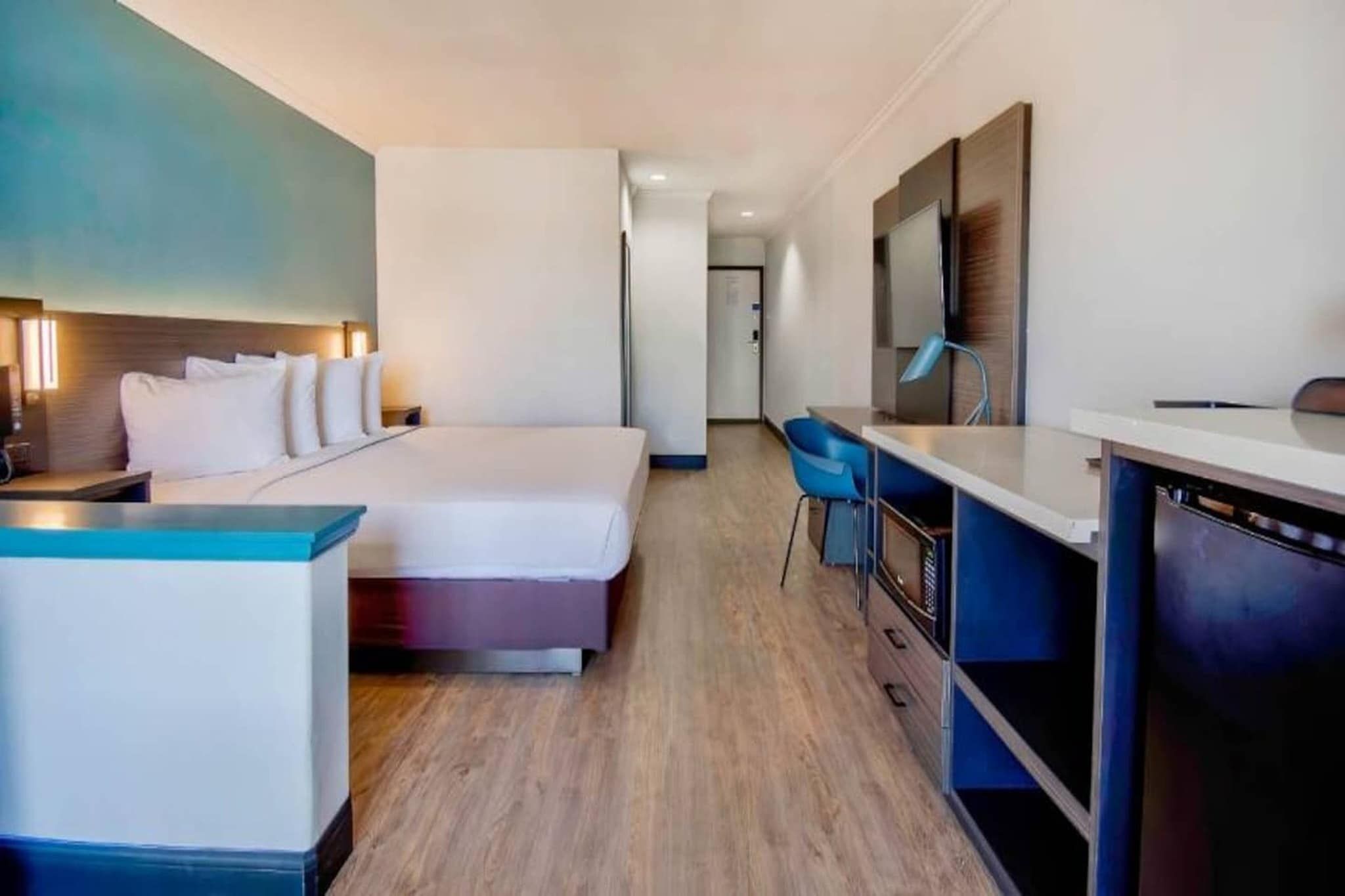 A hotel room with a bed, a desk, and a chair.