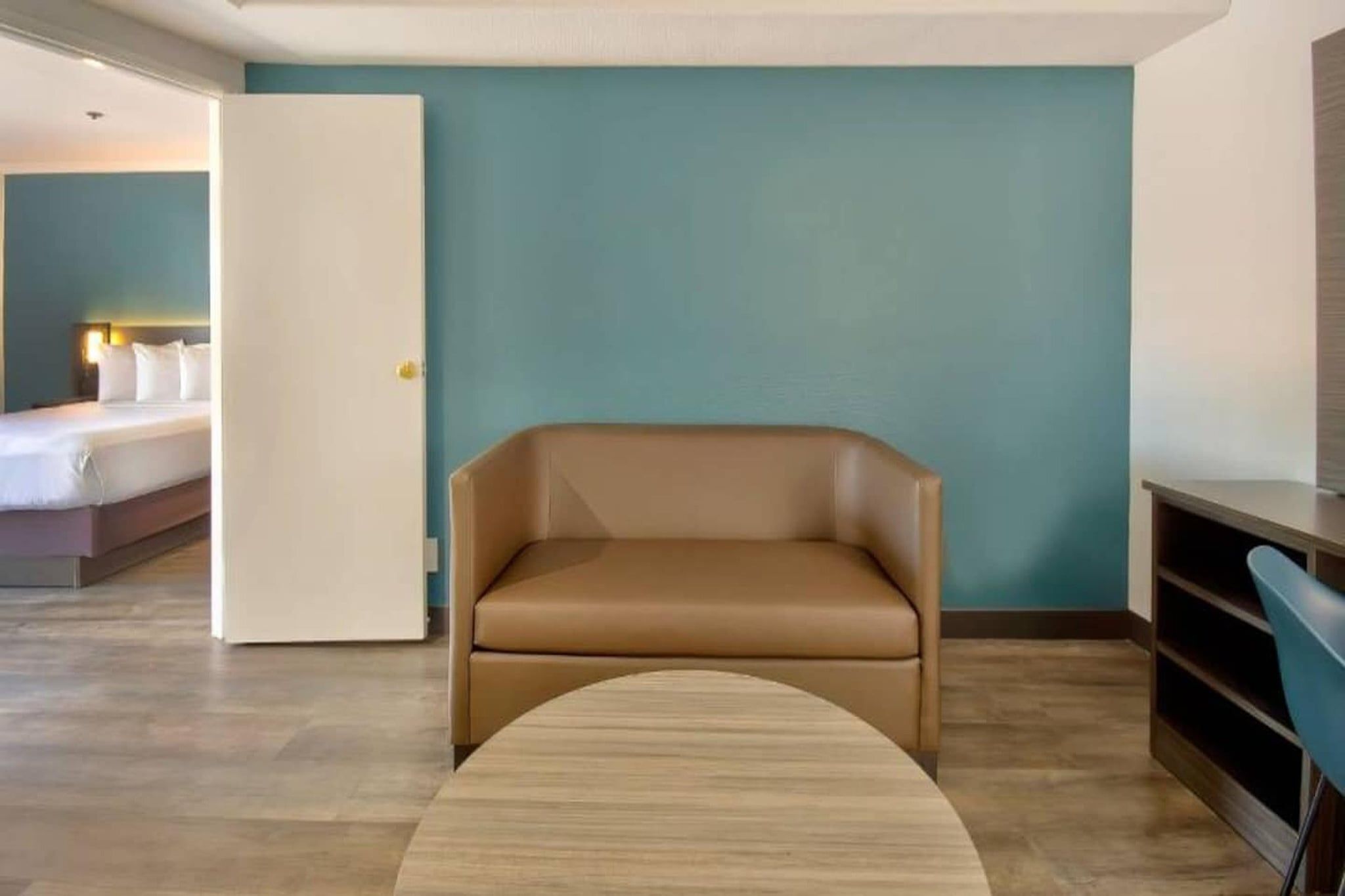 A hotel room with a bed, a sofa, a small table, and a door.