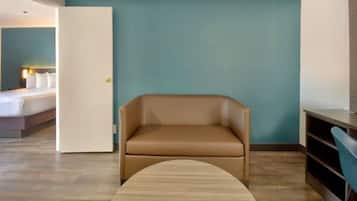 A hotel room with a bed, a sofa, a small table, and a door.