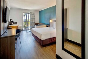 Une chambre d’hôtel équipée d’un lit, d’un bureau, d’une chaise et offrant une vue sur l’extérieur.