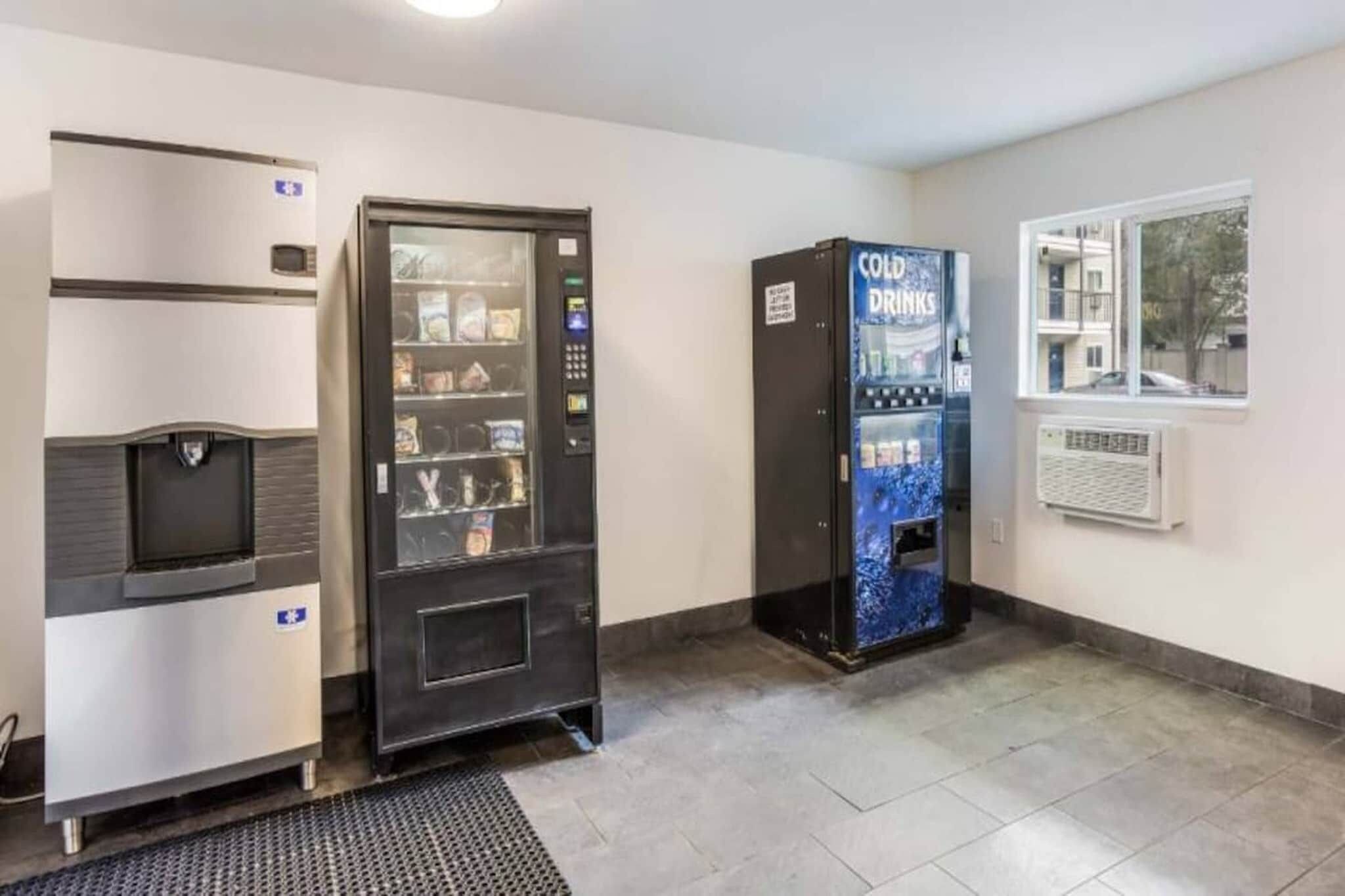 Un espace comprenant un distributeur automatique, un réfrigérateur et une fenêtre donnant sur un paysage agréable.