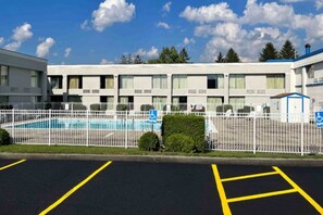 A hotel with a swimming pool, parking spaces, and a fenced area. - 2 Full Beds | Smoking, Kitchen (Clarion)