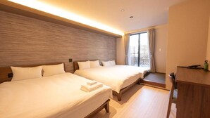 A hotel room with two beds, a wooden headboard, a window with curtains, and a small desk with a chair. - WANOKAEDE HOTEL NEW WING (Tokyo)