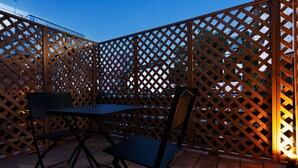 An outdoor patio area with a wooden lattice partition, a metal table, and two chairs. - WANOKAEDE HOTEL NEW WING (Tokyo)