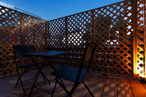 An outdoor patio area with a wooden lattice partition, a metal table, and two chairs. - WANOKAEDE HOTEL NEW WING (Tokyo)