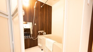 A bathroom with a wooden wall, a white bathtub, and a shower. - WANOKAEDE HOTEL NEW WING (Tokyo)