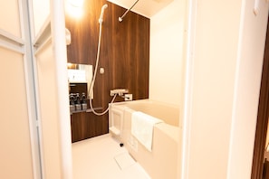 A bathroom with a wooden wall, a white bathtub, and a shower. - WANOKAEDE HOTEL NEW WING (Tokyo)