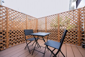 A wooden deck with a lattice fence, two chairs, and a table.