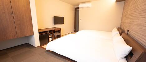 Una habitación de hotel con cama, escritorio, televisión y armario.