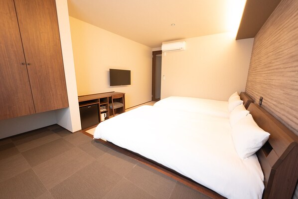 A hotel room with a bed, a desk, a television, and a wardrobe.
