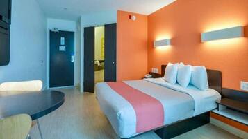 A hotel room with a bed, bedside table, and a desk.