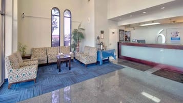 A lobby with patterned sofas, a reception desk, and a large window.